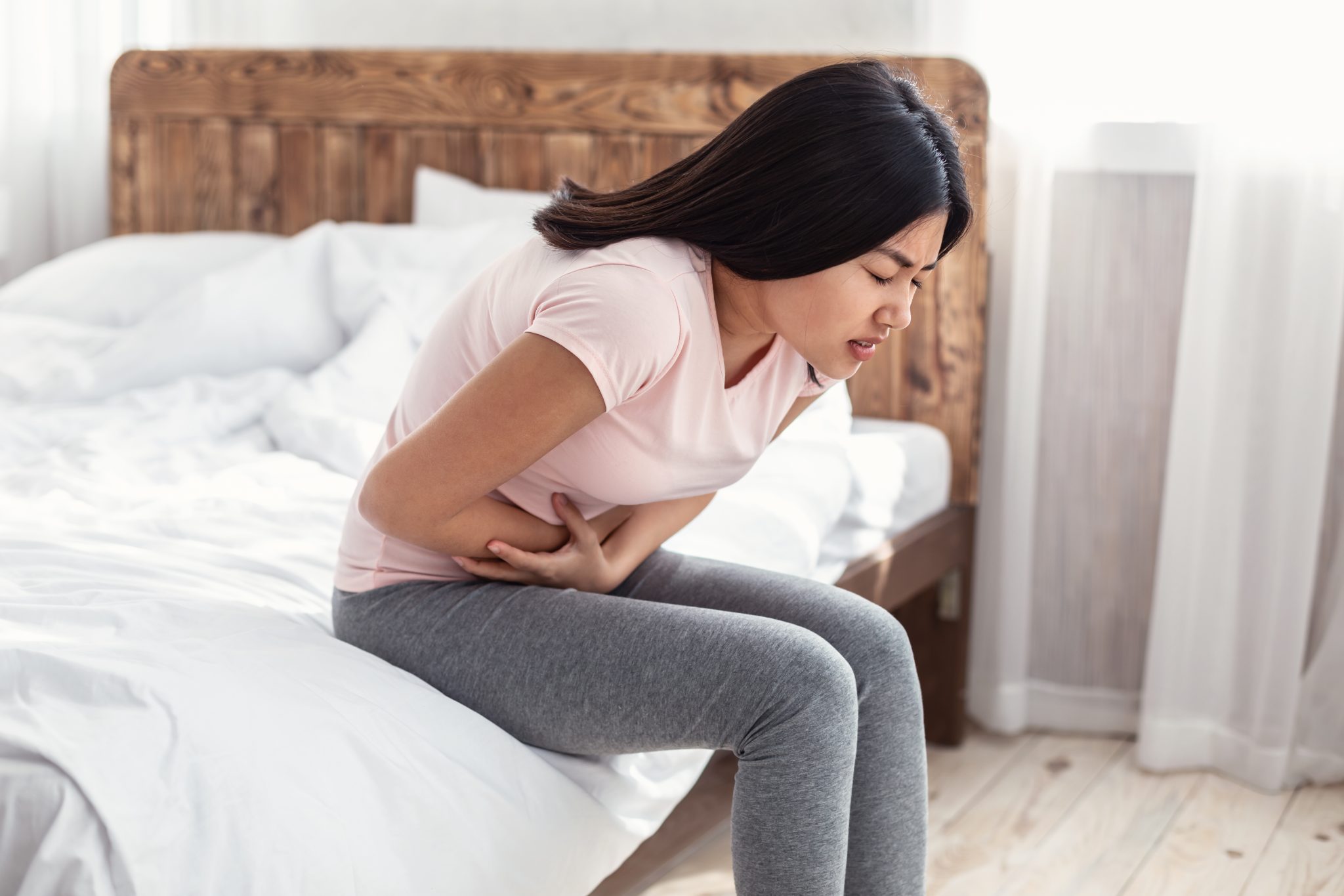 Asian Woman Having Stomachache Suffering From Pain Sitting At Home - Awaken  Chiropractic & Sports Medicine